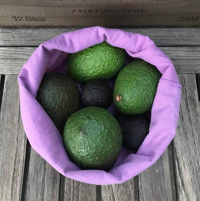 Purple produce bag upcycled from a donated linen sheet, filled with avocados