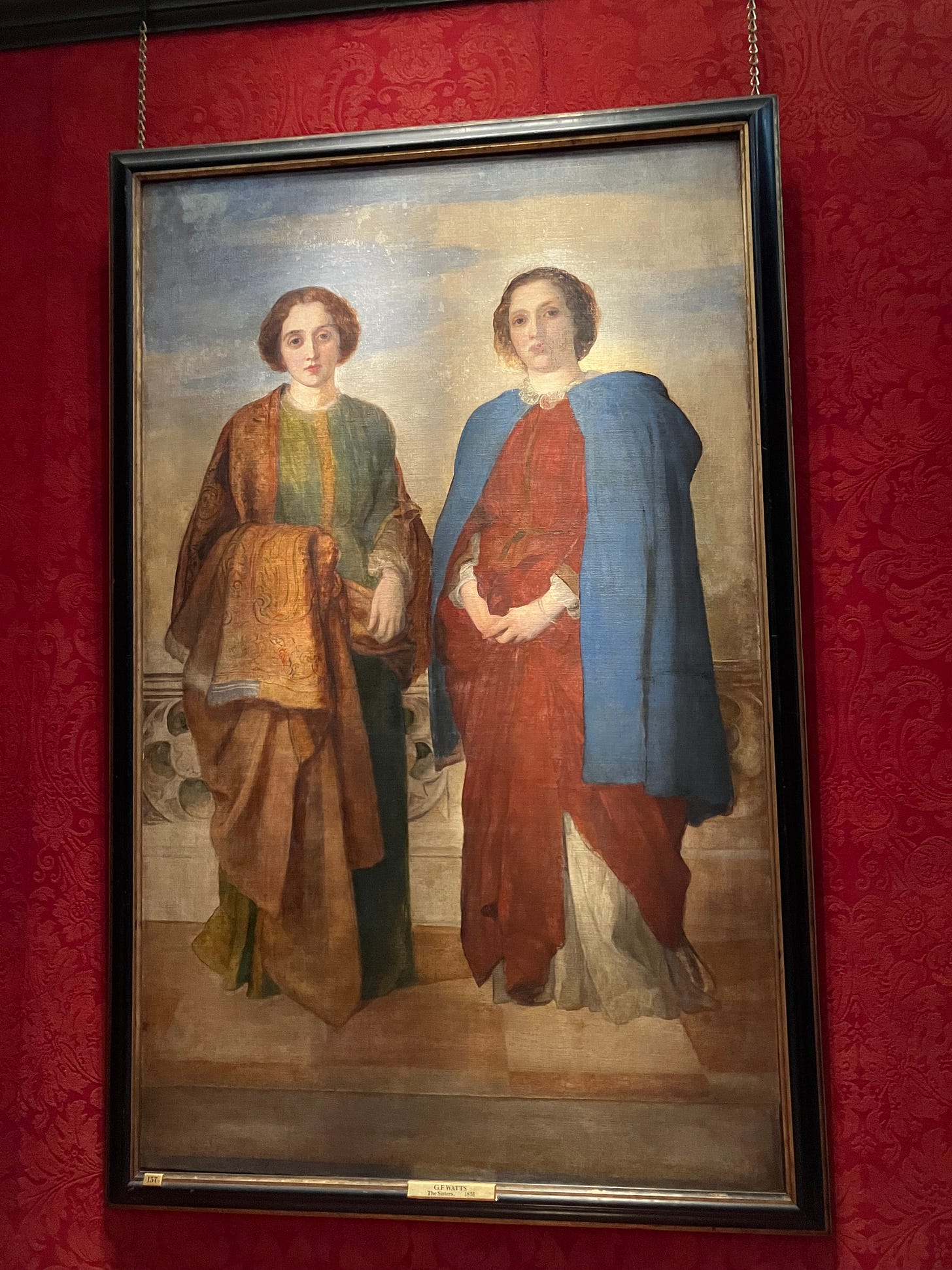 large portrait in greens, blues, and reds of two young women, hair coiled, standing face forward on a tiled floor