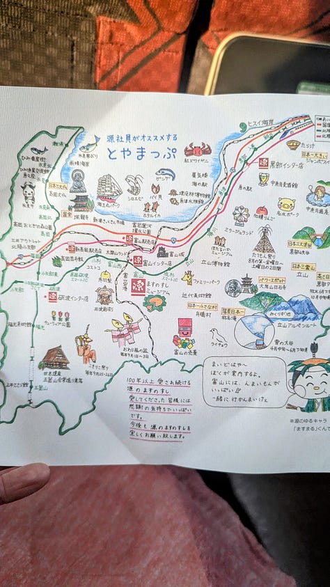 Colorful Japanese dishes inside of an obento lunch box. The box wrapped in a pink furoshiki cloth. An illustrated map inside the cover.