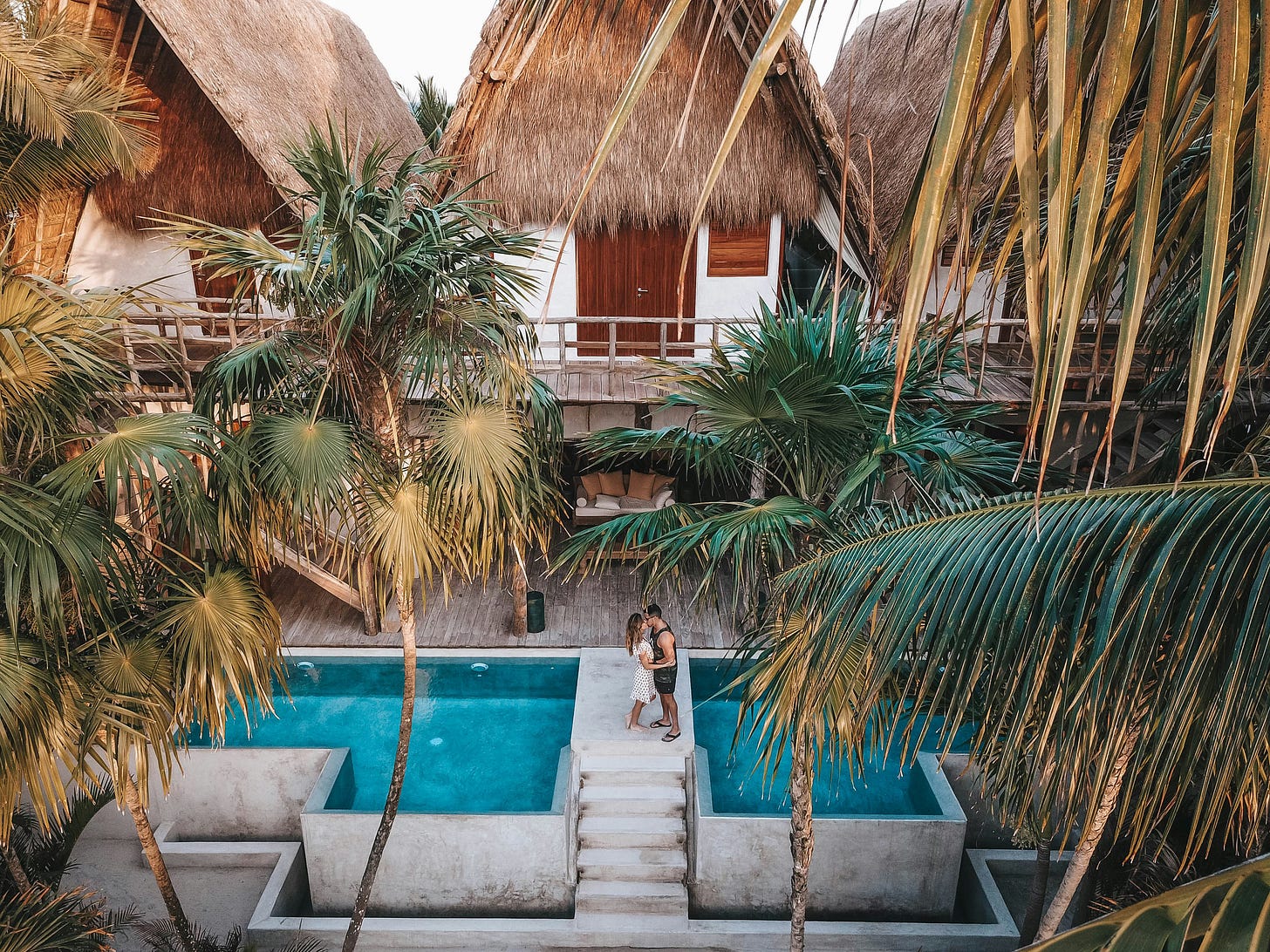 a couple embracing in a paradise hotel with palm trees and pools