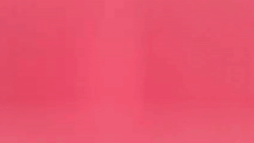 a woman in a leather jacket is dancing in front of a pink background .