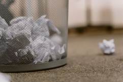 Crumpled up white paper in a waste paper basket, with one ball of paper on the floor. Crumpled up white paper in a waste paper basket, with one ball of paper on the floor.