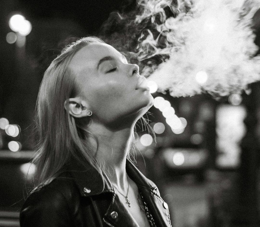 a woman smoking a cigarette in a black and white photo