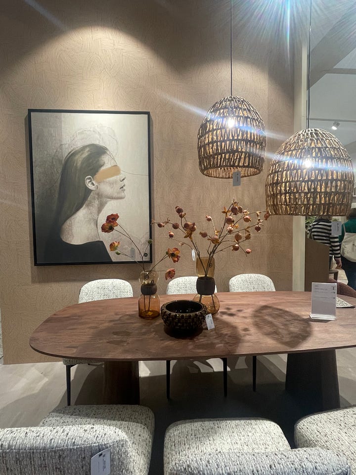 Dining table vignette at Maison & Objet Paris 2026 featuring sculptural pendant lighting, neutral textured walls, artisan tableware, and soft contemporary seating. Modern dining furniture display at Maison & Objet Paris 2026 showcasing upholstered chairs, round wood table, warm earth-tone palette, and layered lighting design.