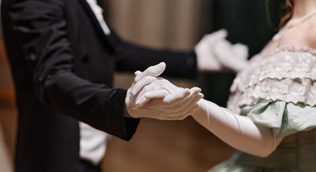 A person wearing a black and white tailcoat and a person wearing a mint green regency dress holding hands and dancing