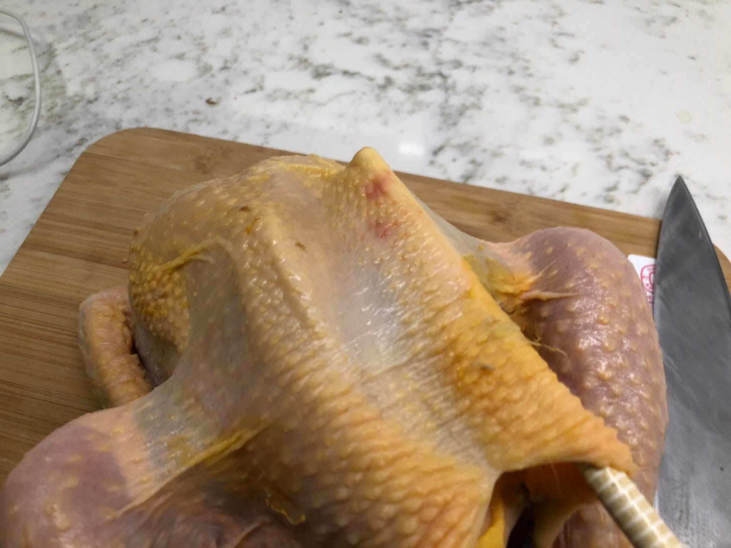 The end of a chopstick pulling the skin away from the chicken breast