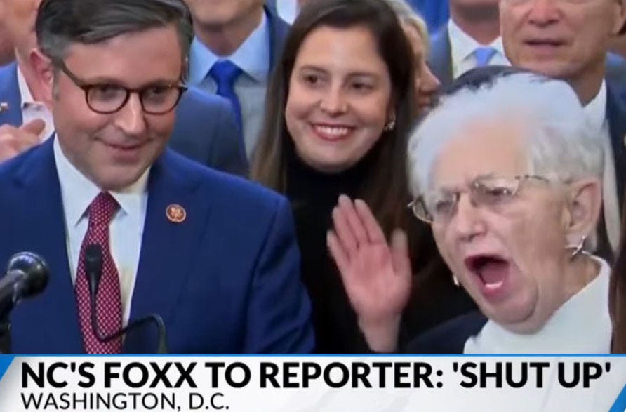 video screenshot of Virginia Fox yelling at a reporter as Speaker Mike Johnson looks on. (Image has been slightly altered to enlarge the portion of the screenshot including Foxx and to move the chyron closer to her yelling face)