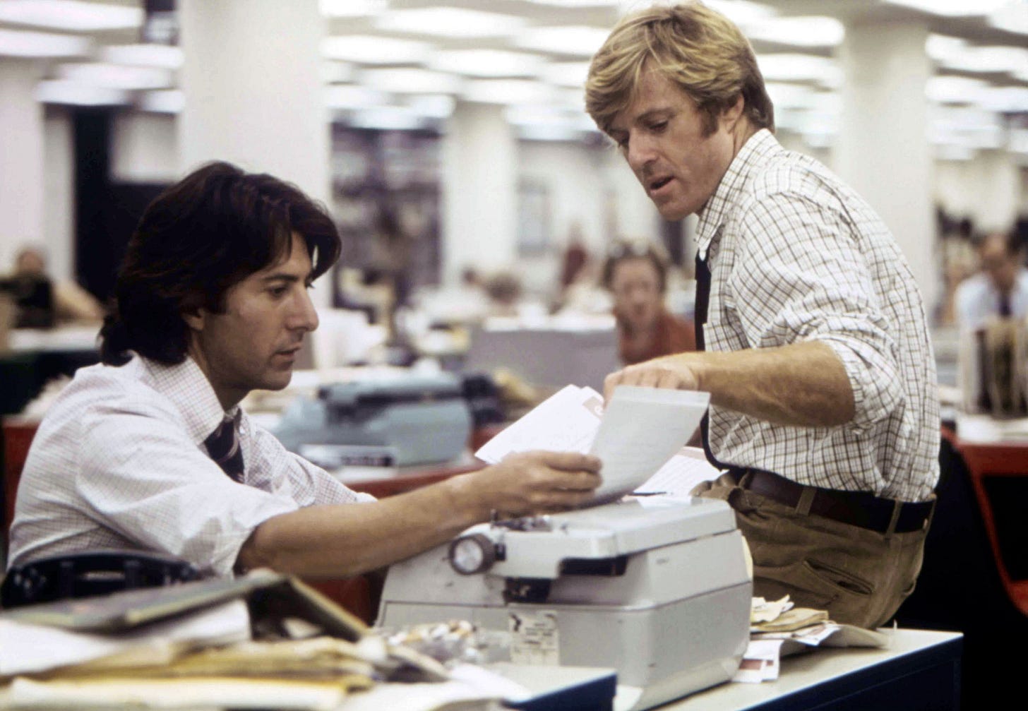 Dustin Hoffman and Robert Redford look at typewritten pages in All the President's Men.