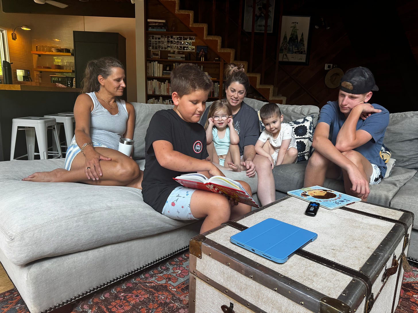 Family and children sit together on a large couch, gathered for a relaxed moment at the lake house, highlighting the lasting impact of an uncle’s influence that brought them together to share joyful traditions and create new memories.