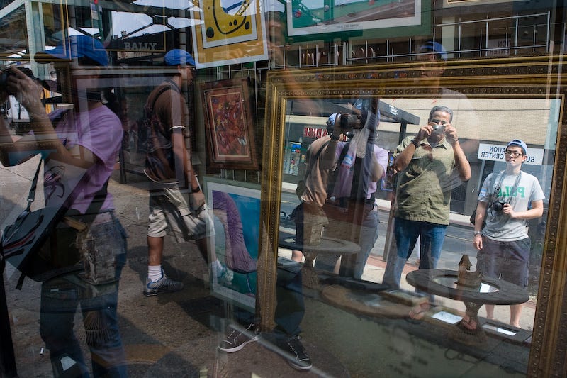 O fotógrafo Ed Kashi e seus alunos diante de uma vitrine com espelhos e molduras no Queens, em Nova York.