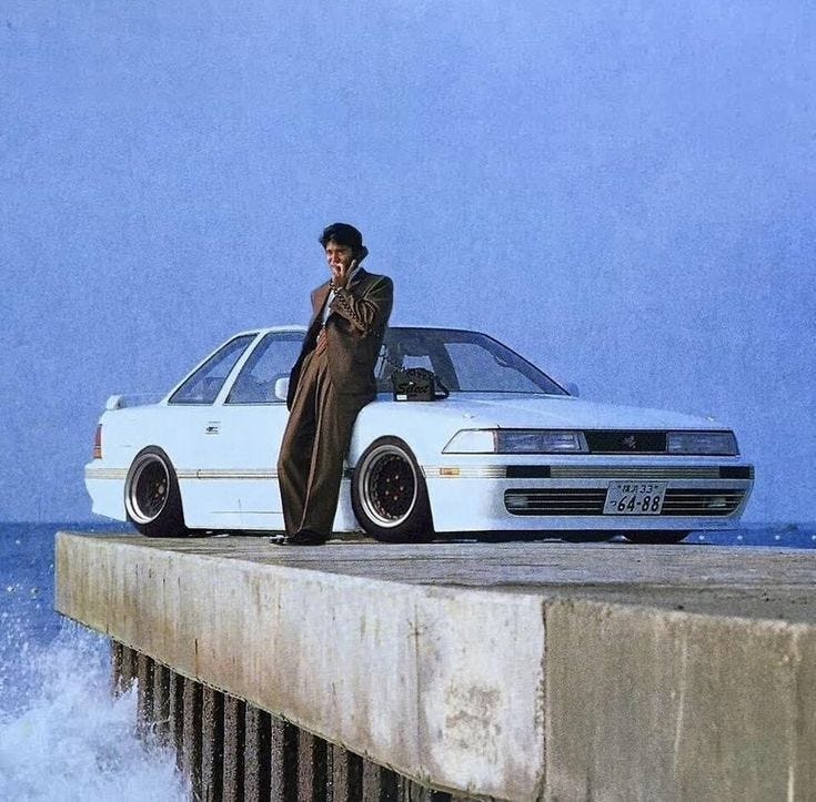 This may contain: a man standing next to a white car on top of a pier near the ocean