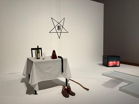 Left: a woman in a lab coat in a video projection narrates the work; Center: the remnants of a burned star from one of Abromovic's earliest installations with black and white photographs of the fire on the wall; Right: the table and star set-up of a live installation when Abromovic carved the star symbol into her abdomen as a performance.