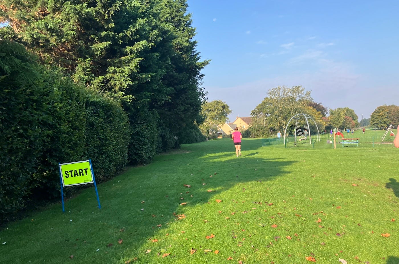 A hedge borders the field, a playground on one side