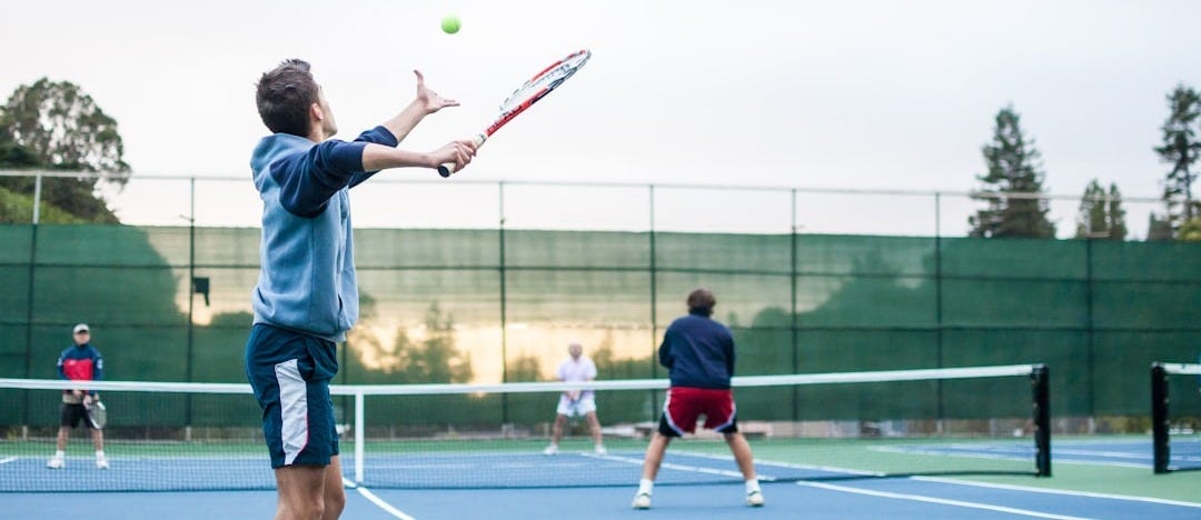 four men playing double tennis during daytime