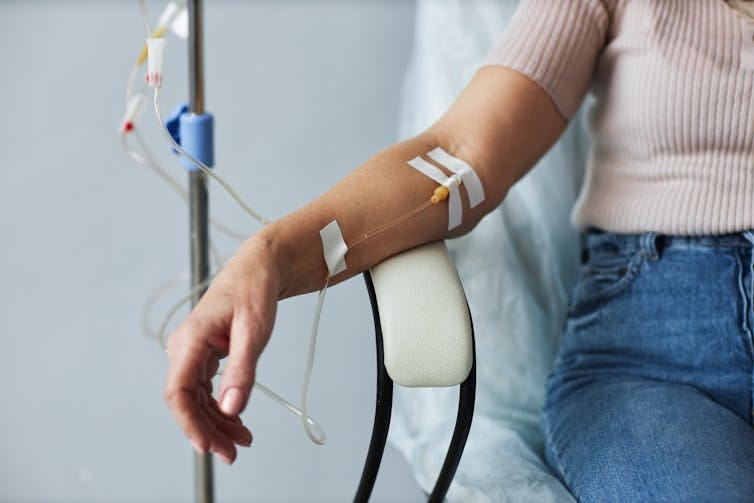 Close-up of arm with IV line placed, resting on chair Close-up of arm with IV line placed, resting on chair