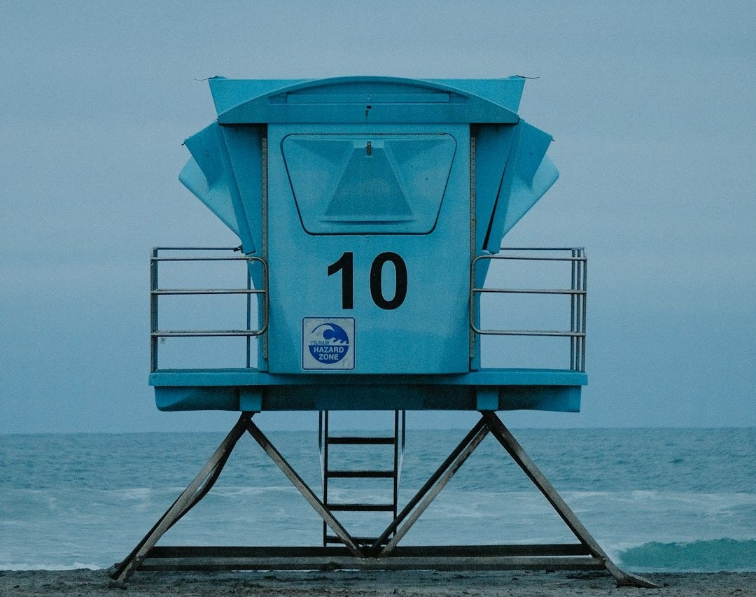 a lifeguard tower sitting on top of a sandy beach a lifeguard tower sitting on top of a sandy beach