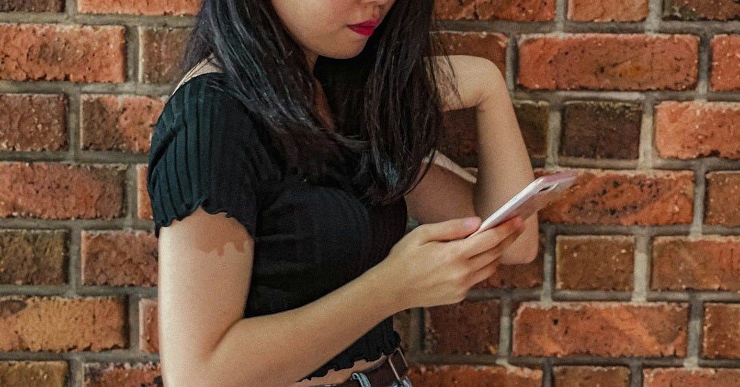 a woman standing next to a brick wall