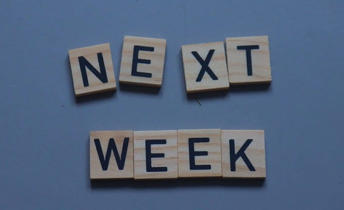 scrabble tiles spelling the word next week on a blue background