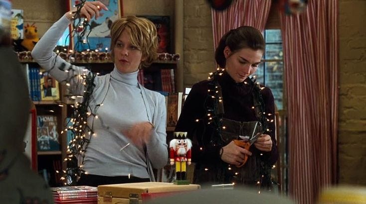 This may contain: two women standing in front of a book shelf with christmas lights on the bookshelves
