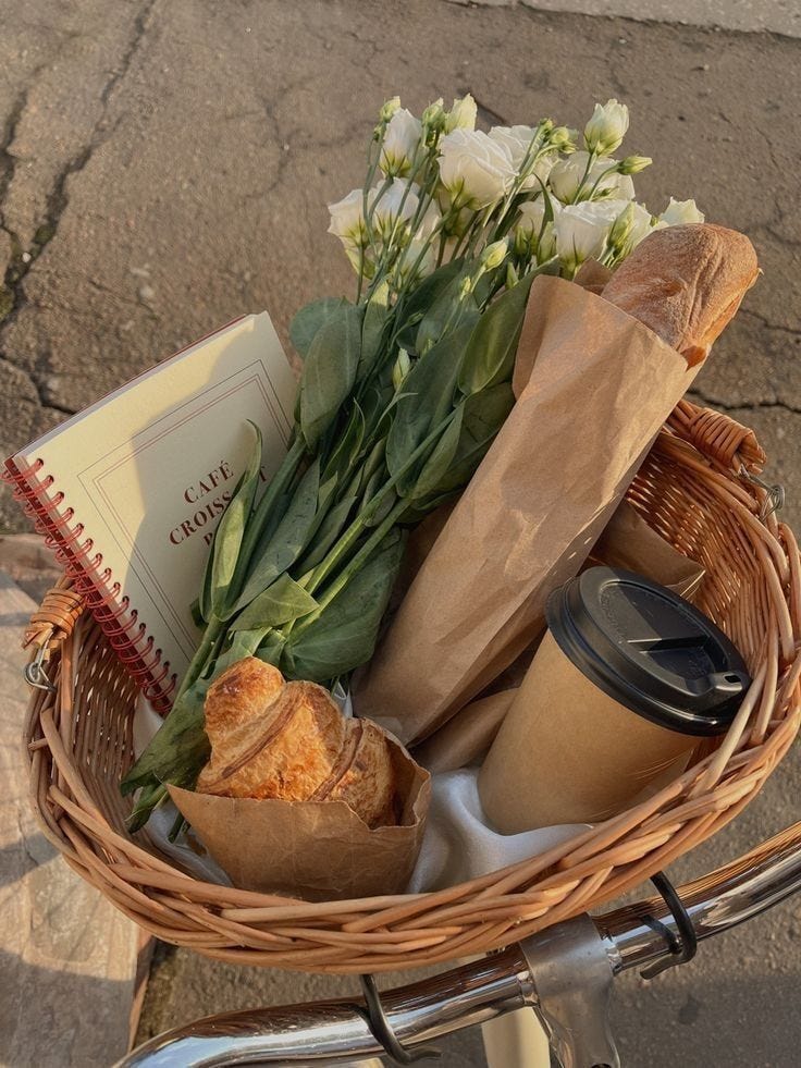 This may contain: a basket filled with bread and flowers on top of a bike