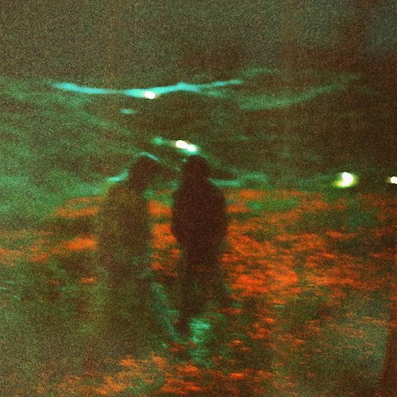This may contain: two people are standing in the woods at night with green and red lights on them