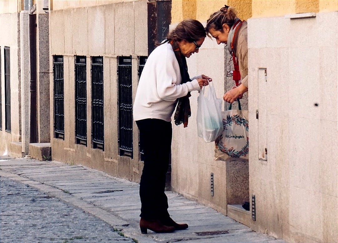 woman in white long sleeve shirt and black pants standing on sidewalk during daytime