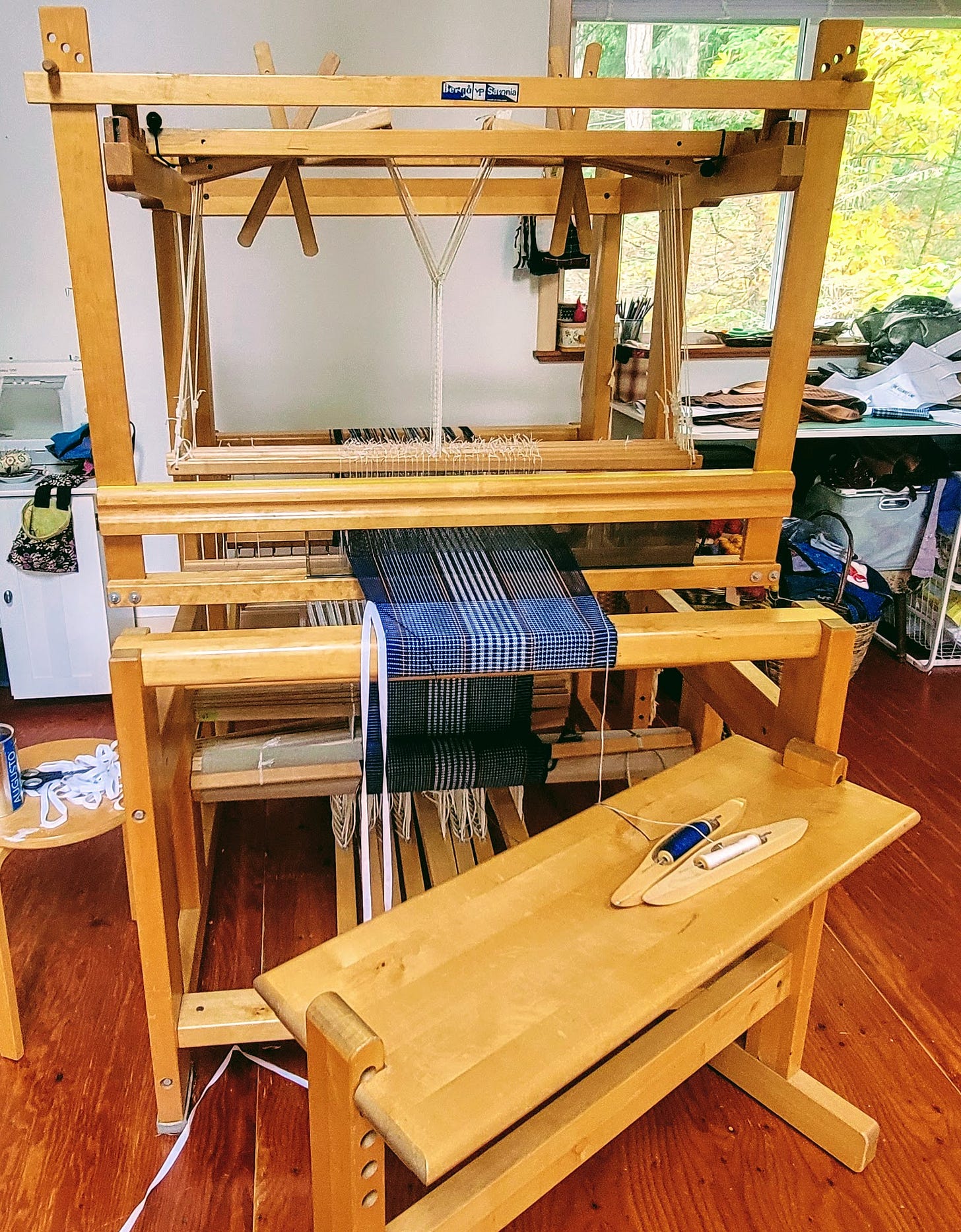 A weaving loom with some weaving on it, messy table in the background. A weaving loom with some weaving on it, messy table in the background.