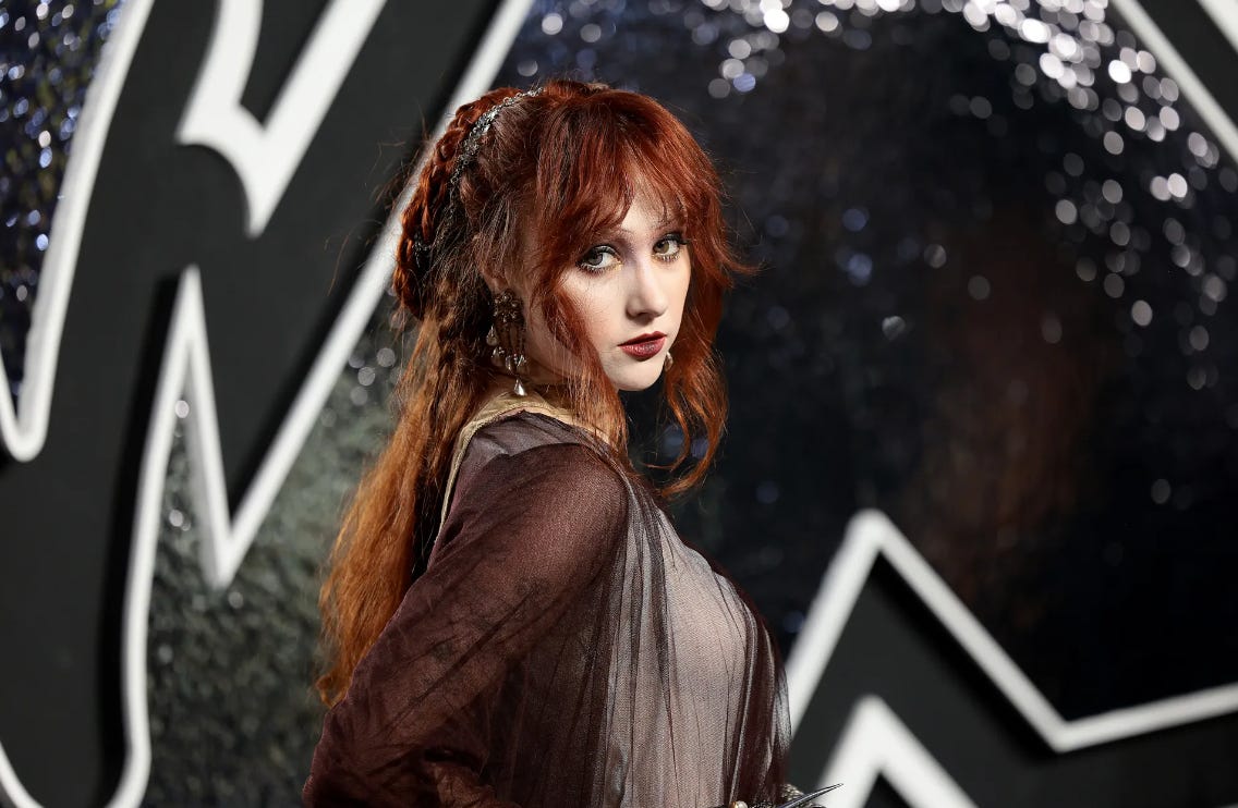 Chappell Roan dressed in a black and beige gown with red hair framing her face.