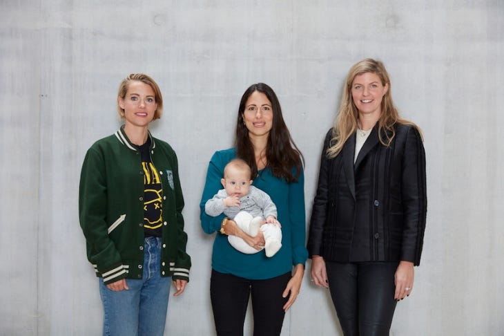 3 women standing, one holding a baby