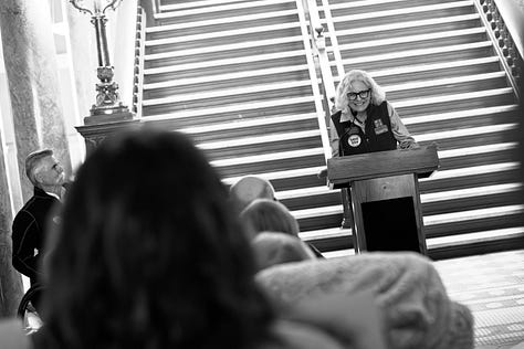 A gallery of black and white photos of a rally in the rotunda of Montana's state capitol. people are holding signs in support of disability rights, there is a podium with legislators speaking, people with a virety of physical disabilities are throughout the crowd.