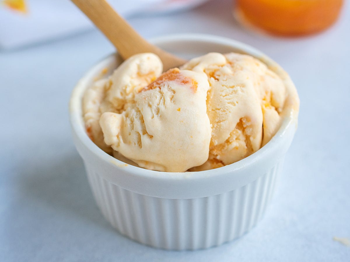 Apricot ice cream in a white ramekin with a wooden spoons. Apricot ice cream in a white ramekin with a wooden spoons.