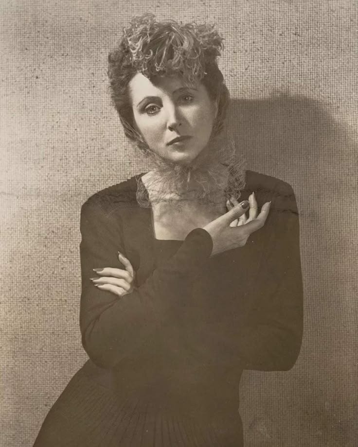 This may contain: an old black and white photo of a woman with her hands on her chest, posing for the camera