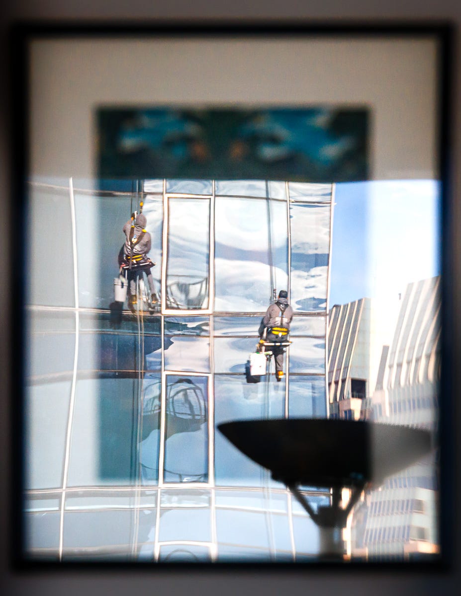Mysterious framed reflection of a window washer, with room elements blending in. Mysterious framed reflection of a window washer, with room elements blending in.