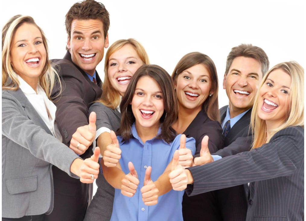 Group of 7 people dressed in business suits giving thumbs up with wide grins