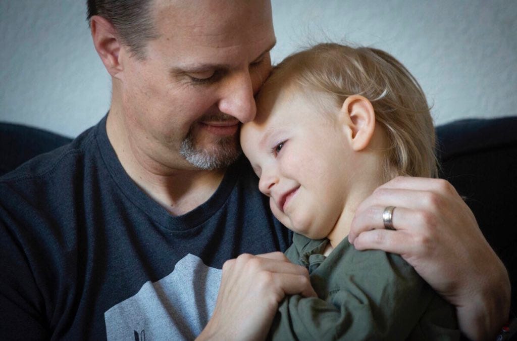 A close up photo of a man hugging his young daughter.