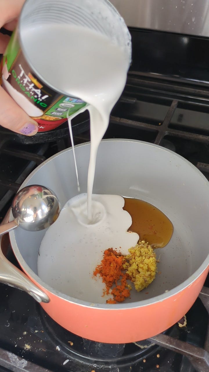 Golden milk ready to drink. Fresh grated turmeric and ginger with ground cinnamon and cardamom, honey and coconut milk getting ready to simmer.