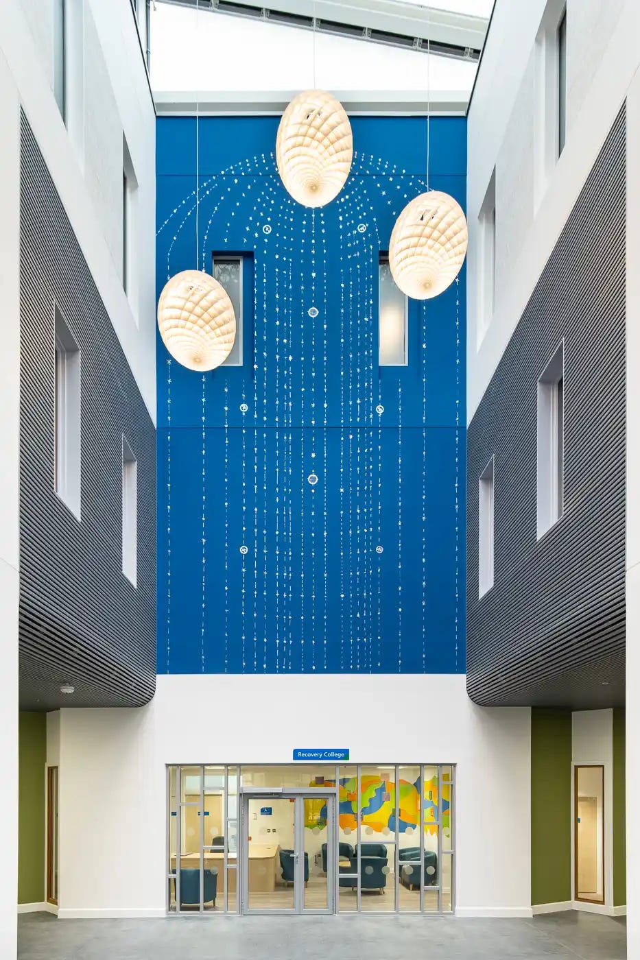 An art installation by Sutapa Biswas in the atrium of Springfield Hospital, featuring blue panels with intricate dotted patterns and large sculptural hanging lights.