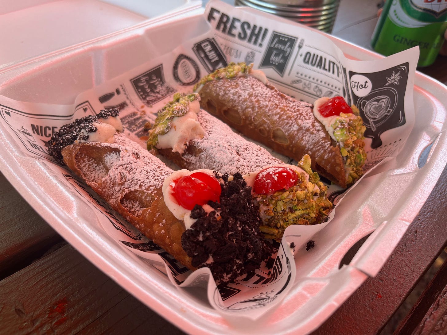 three cannolis in a styrofoam box