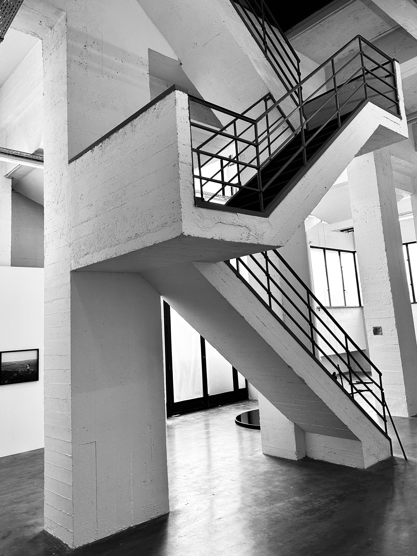 A concrete interior staircase in a gallery space that when viewed from my angle appears to resemble "K".