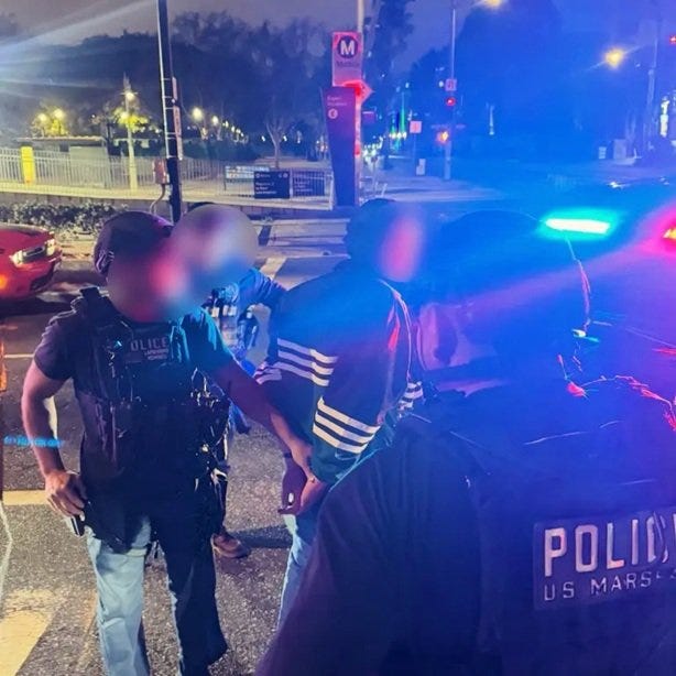 Police officers apprehend a suspect during a nighttime operation, with flashing lights from a patrol vehicle illuminating the scene. Police officers apprehend a suspect during a nighttime operation, with flashing lights from a patrol vehicle illuminating the scene.