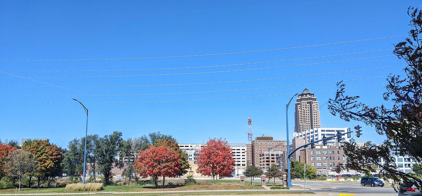 A photo of downtown Des Moines from an autumnal tree lined MLK against a bright blue, cloudless sky