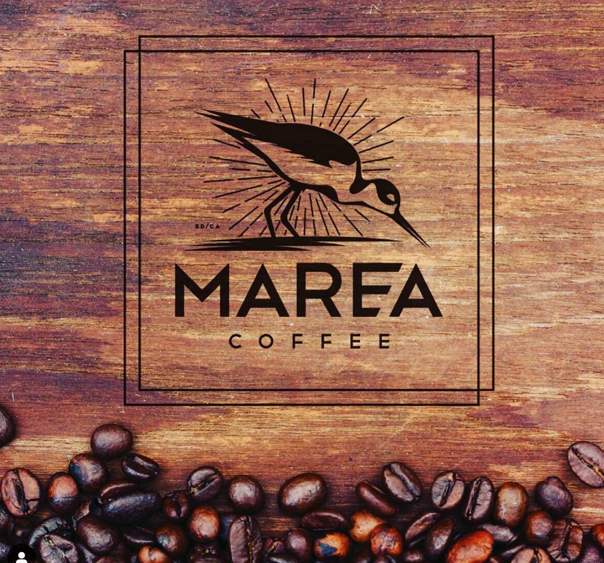 Marea Coffee logo of a bird superimposed over a piece of stained brown wood with coffee beans sprinkled along the bottom. Marea Coffee logo of a bird superimposed over a piece of stained brown wood with coffee beans sprinkled along the bottom.