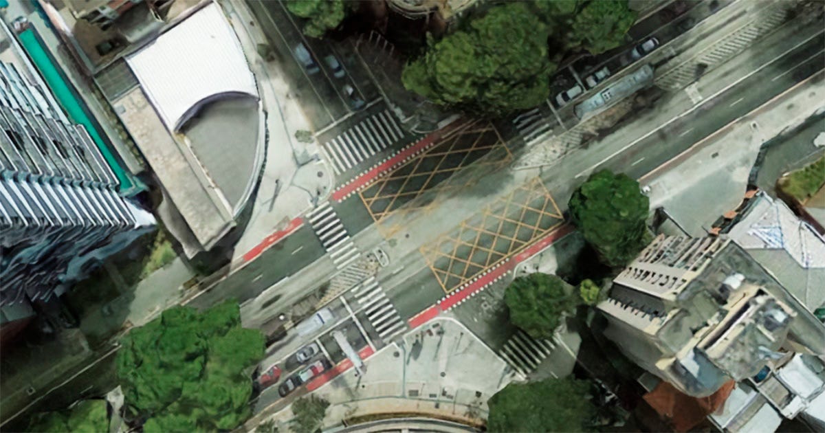 : Fotografia aérea do cruzamento entre a Avenida Rebouças e a Rua Oscar Freire, em São Paulo. O entorno é composto por prédios altos e copas de árvores, ilustrando o fluxo intenso e a infraestrutura de trânsito analisada no estudo de microssimulação