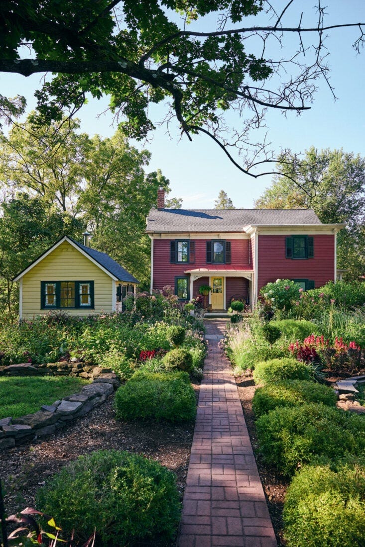 A red house with a lush garden and yellow shed A red house with a lush garden and yellow shed