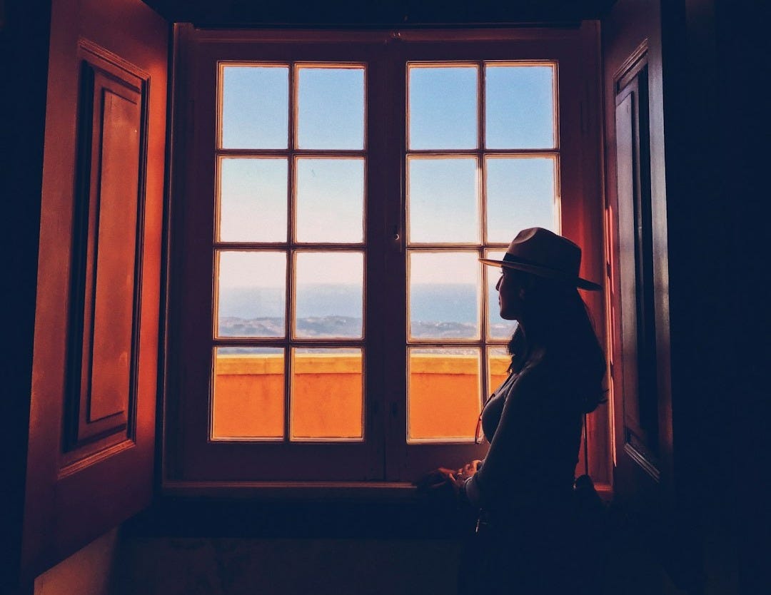 woman standing beside window woman standing beside window