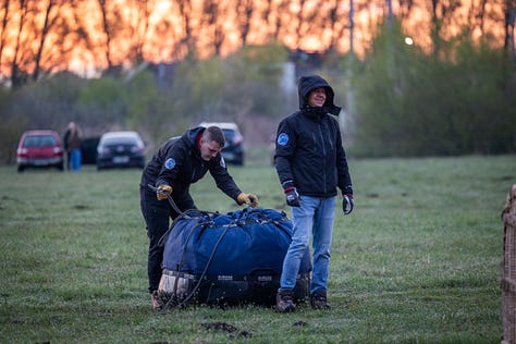 Înainte ca baloanele să urce, totul începe jos, pe iarbă, în frigul subțire al dimineții sau în lumina care abia se stinge peste câmp. Oamenii își ocupă locurile, verifică arzătoarele, întind pânza, ridică nacela, privesc cerul și, mai ales, ascultă vântul. În jur, mașinile stau cu farurile aprinse.