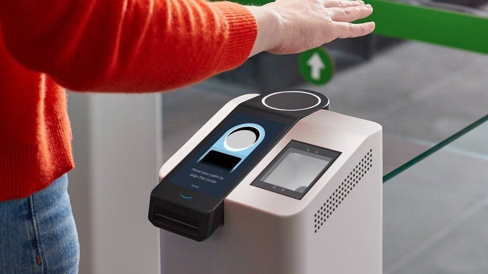 A person's arm and torso in frame show them holding a hand over a scanning terminal which has a ring pointing upwards, and the instruction to "move your palm to align the circles" A person's arm and torso in frame show them holding a hand over a scanning terminal which has a ring pointing upwards, and the instruction to "move your palm to align the circles"