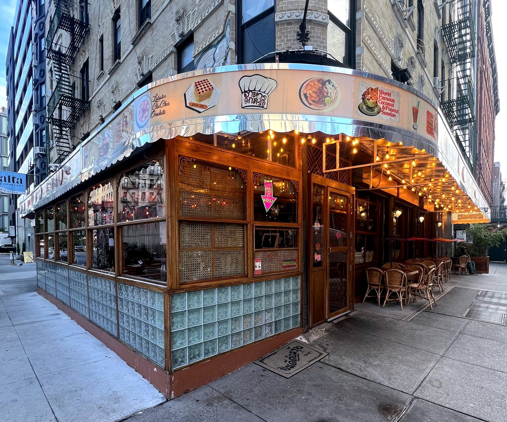 Exterior of Thai Diner corner restaurant in Nolita Manhattan with vintage diner signage, bamboo-woven walls and golden afternoon light