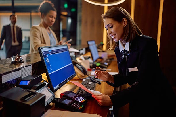 Happy receptionist going through paperwork during guest registration at the hotel. Happy hotel manager filling out registration documents during guest check in at reception desk. hotel front desk stock pictures, royalty-free photos & images