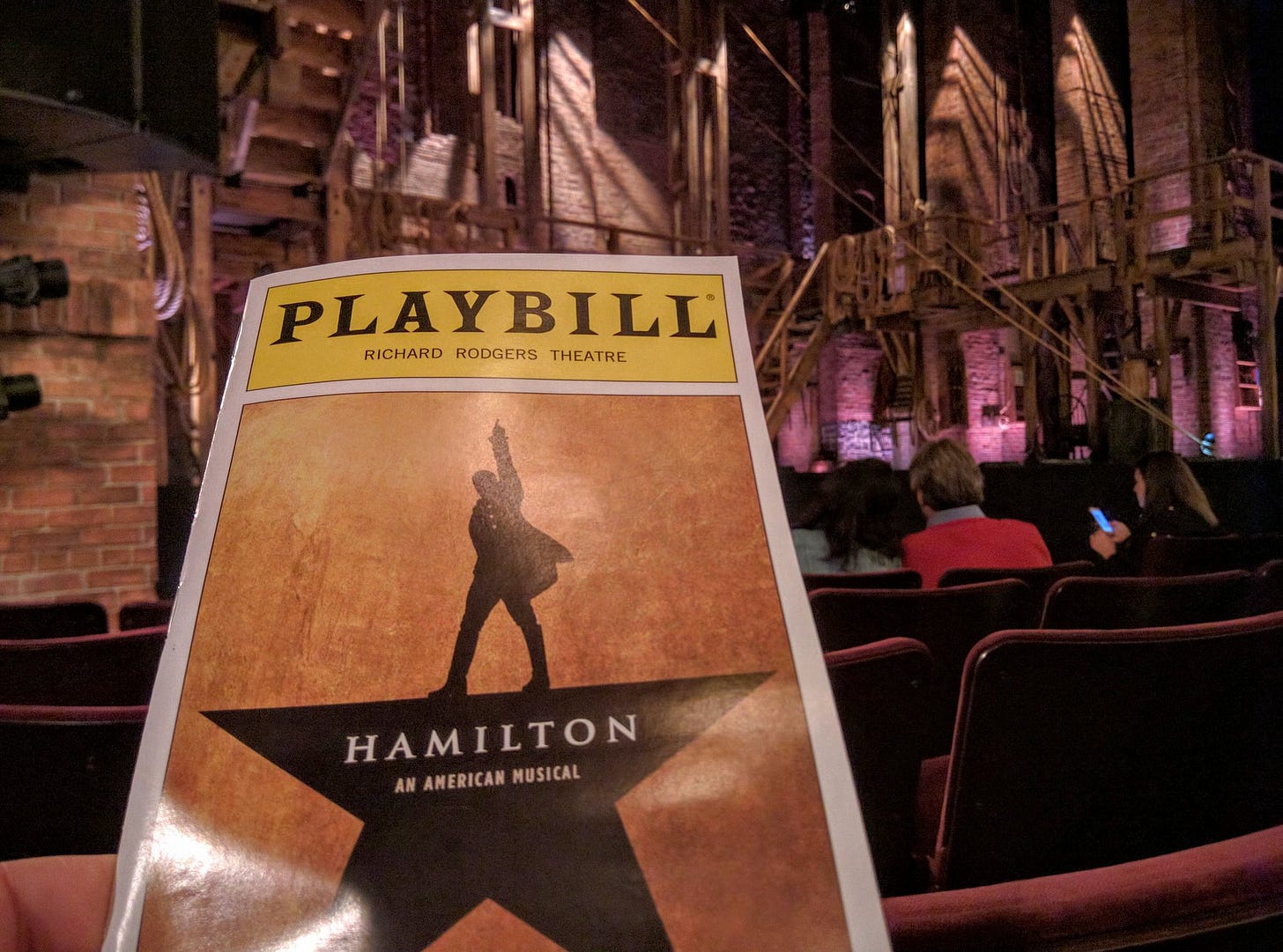 Photo of Playbill for Broadway production of Hamilton held up in theater before play begins.
